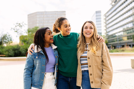 Three happy multiracial young women friends laughing outdoorsの写真素材