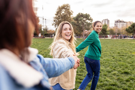 Three young multiracial female friends having fun running together outdoorの写真素材