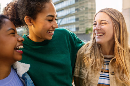 Three young women hugging and laughing outdoors