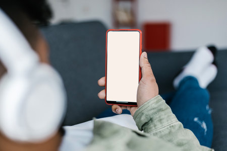 Young man lying on the sofa and holding phone with blank screen