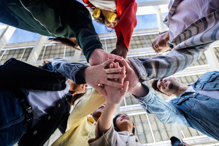 Low angle view of young people stacking hands outdoor