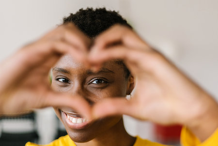 Young smiling lovely multiracial woman showing shape heart with hands