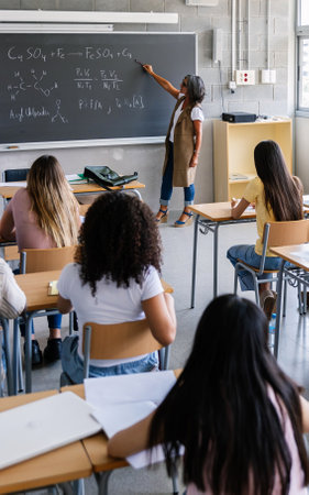 Diverse high school students listening to female teacher in classroomの写真素材