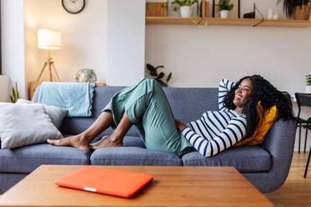 Young woman relaxing on sofa at home enjoying free timeの写真素材