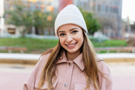 Young woman in winter clothes smiling at camera standing at city streetの写真素材