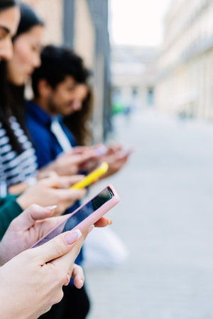 Vertical shot of young group of people using mobile phones at city streetの写真素材