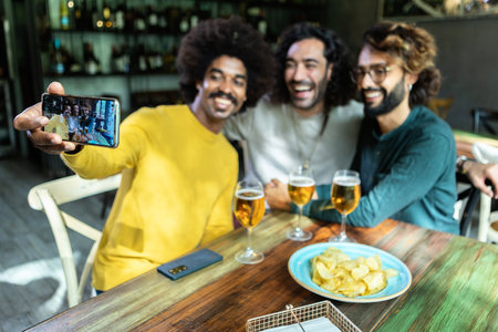 Happy friends taking selfie and drinking beer at the barの写真素材