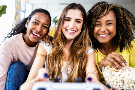 Laughing multicultural teens using joystick while playing video games at homeの写真素材