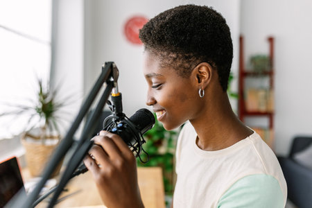Happy black creative woman recording a podcast using a professional microphoneの写真素材