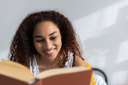 Young happy latin american woman reading a book in her bedroom