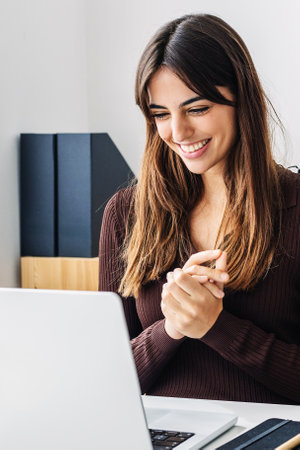 Vertical photo of young beautiful woman having a video call on laptop from home
