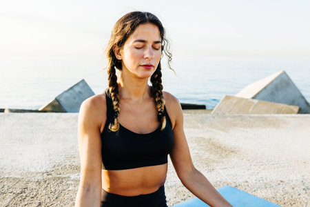 Mid adult woman sitting on lotus position practicing yoga meditation outdoorsの写真素材