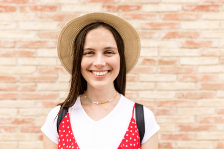 Young female tourist smiling while looking at camera in front of wallの写真素材