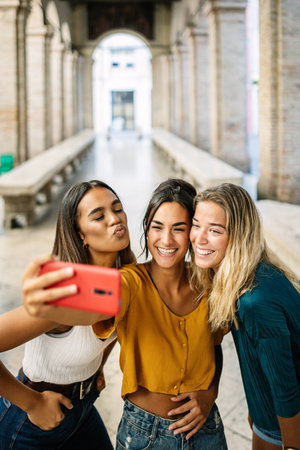 Group of multiracial young women taking selfie photo on cellphone outdoor