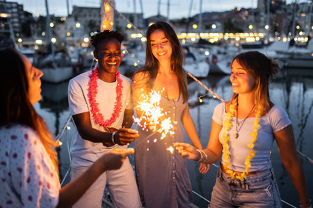 Multiracial friends celebrating boat party with sparklesの写真素材
