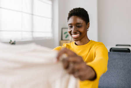 Young woman checking new clothing item after receive online purchase at homeの写真素材