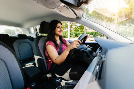 Young adult happy indian woman driving a car in the city.