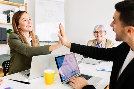Business team giving high five after successful business plan presentation