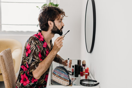Man applying mascara while looking in the mirror:の写真素材
