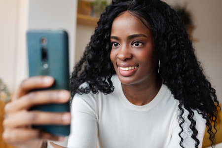 Smiling woman using smartphone at home for video callの写真素材