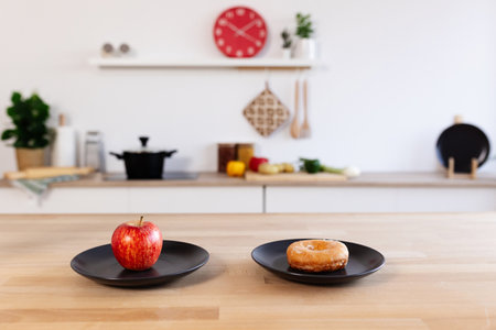 Wooden table with a red apple and a doughnut on two black plates