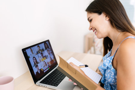 Happy woman taking notes while attending online meetingの写真素材