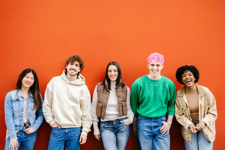 Happy multiracial young friends standing over isolated red urban background