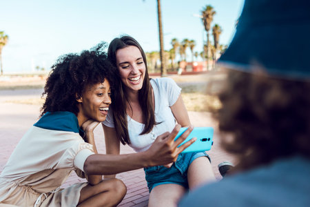 Two happy female friends taking a selfie with smartphone outdoors