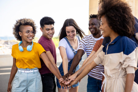 Diverse group of young people stacking hands together outsideの写真素材