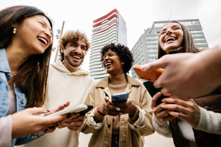 Young group of happy friends having fun using smart phones outdoors