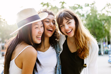 Three young smiling women laughing together walking in city street