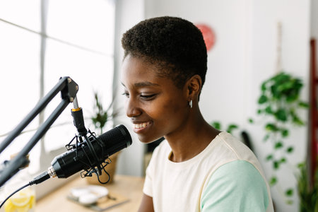 Young woman recording a podcast from home using a professional microphoneの写真素材