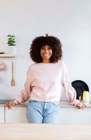 Vertical portrait of young beautiful woman standing in the kitchenの写真素材
