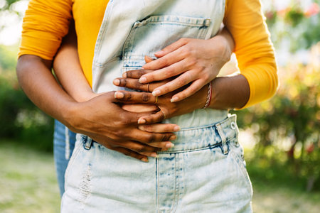 Interracial lesbian couple embracing outside, showing affection and intimacyの写真素材