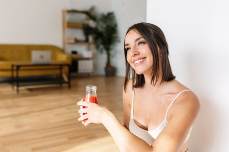 Beautiful young woman in sportswear drinking detox juice after fitness workoutの写真素材