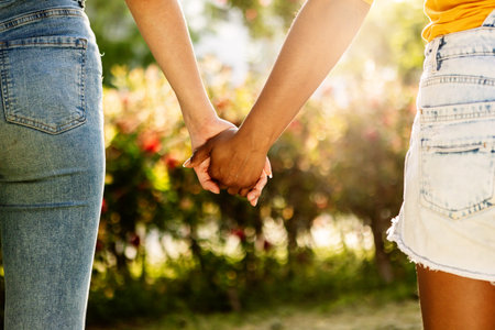 Interracial lesbian couple holding hands in a parkの写真素材