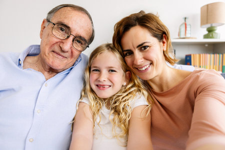 Cheerful portrait of little cute girl with her grandfather and mother at home.の写真素材
