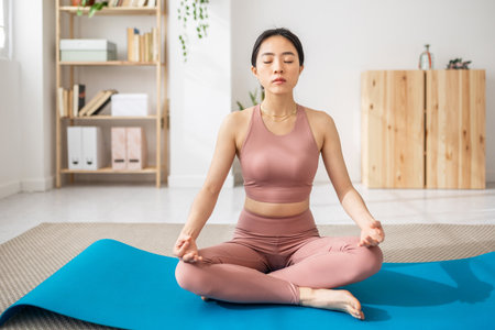 Young asian woman sitting on mat lotus pose do yoga exerciseの写真素材
