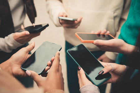 Close view of young people hands using mobile phones in circle outdoorsの写真素材