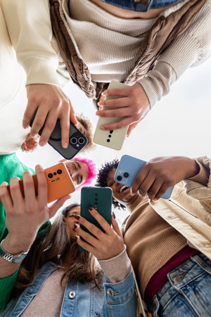 Close up low angle of young students hands holding mobile phones in a circle