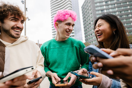 Diverse young friends having fun using mobile phones at city street