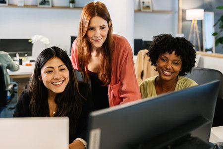 Three young women working together on a laptop in the officeの写真素材