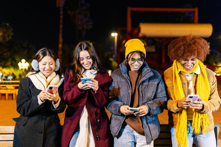 Happy millennial people using smart phones devices together outdoors on winter.の写真素材