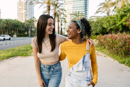 Two multiracial female friends laughing together outdoorsの写真素材