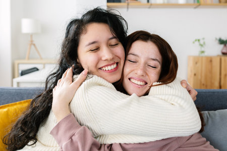 Close up view of happy young millennial women friends hugging each other at homeの写真素材