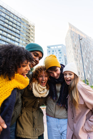 Young diverse joyful gen z friends enjoying winter day together at city streetの写真素材