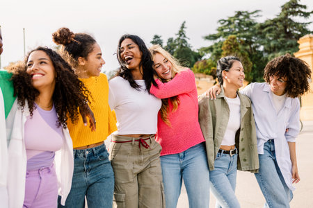 Group of diverse young women walking together laughing outdoorsの写真素材