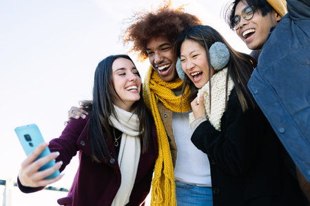 Diverse group of teenage friends having fun taking selfie portrait on winterの写真素材