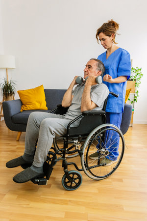 Senior man lifting weights with nurse assistance in living roomの写真素材