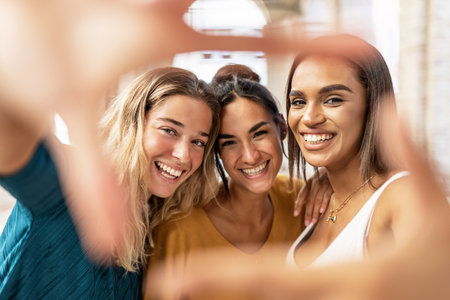 Three multiracial female friends making hand frame gestureの写真素材